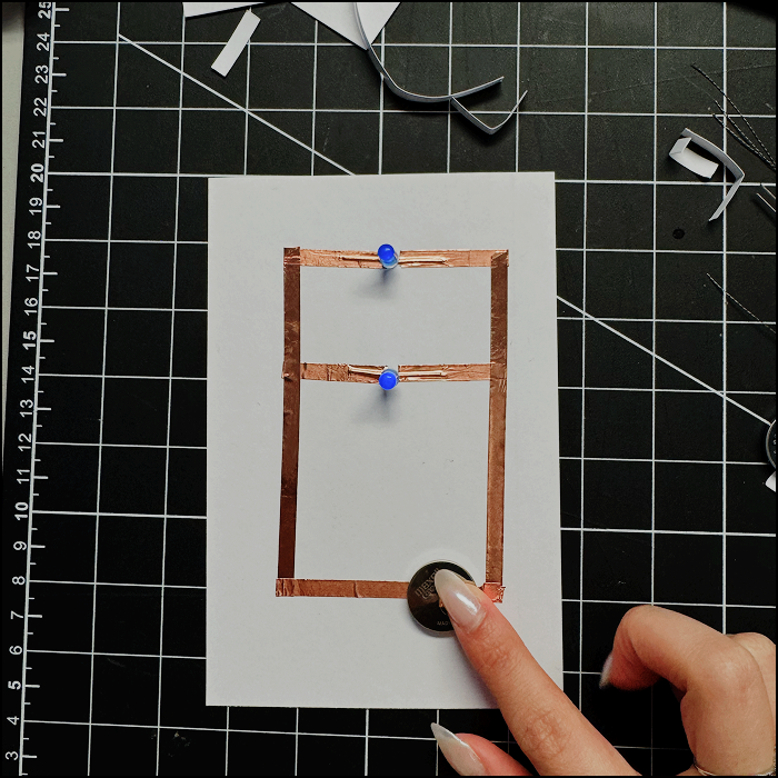 Image of completed parallel circuit with only 1 battery pressed down by the positive side of the circuit (copper tape)