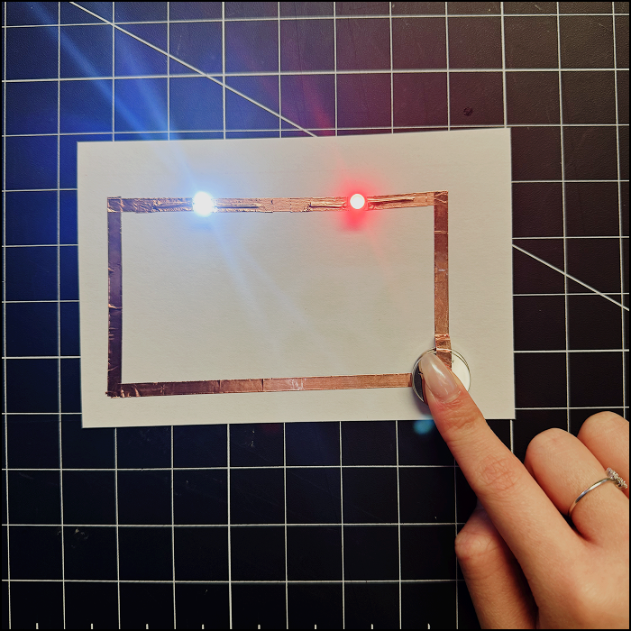 Image shows the series circuit attempt revised with 2 batteries instead of 1 (stacked) and pressed to the positive side of the current (copper tape) and finally working.